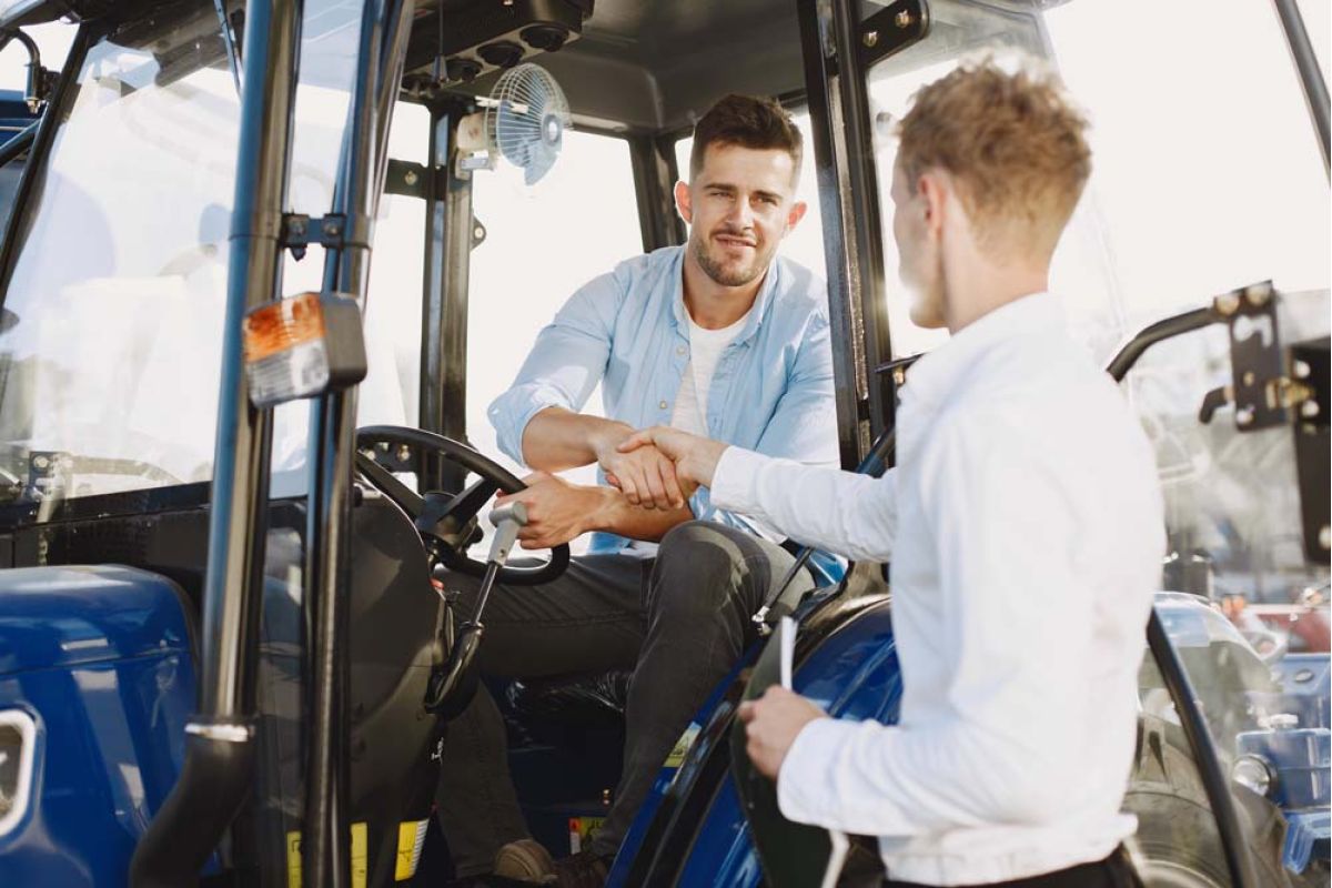 Man in a tractor shaking another man's hand.
