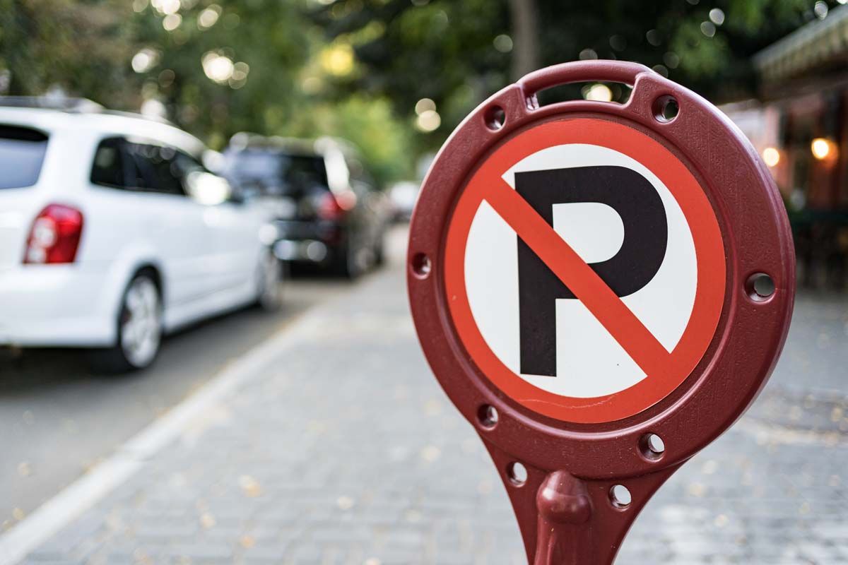 A red and white no parking sign placed on the side of the road, indicating parking restrictions.