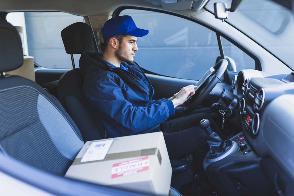 A man in a blue hat sits in the driver's seat of a car.